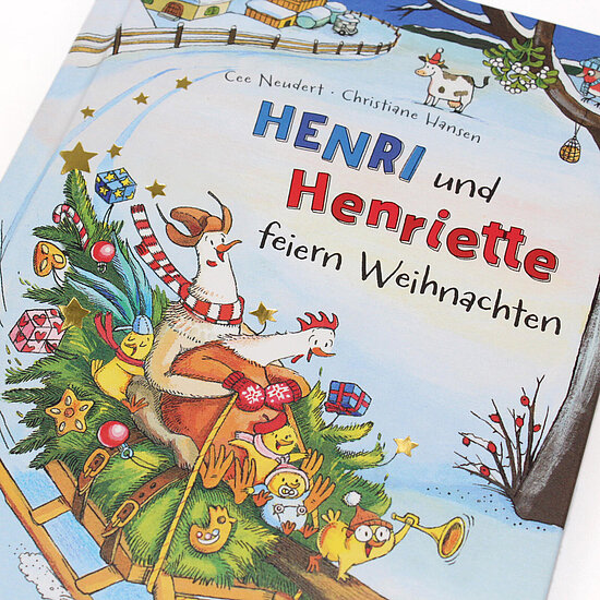 Das Buchcover zeigt … eine Ziege und ein Huhn auf einem geschmückten Tannenschlitten mit Küken, Geschenken und roten, grünen und blauen Farben.