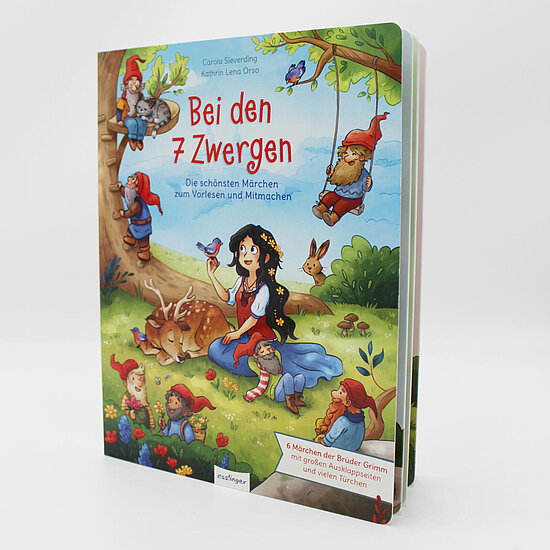 Das Buchcover zeigt Schneewittchen mit dunklen Haaren im blauen Kleid auf grüner Wiese, umgeben von sieben Zwergen mit roten Mützen, Reh und Vögeln.
