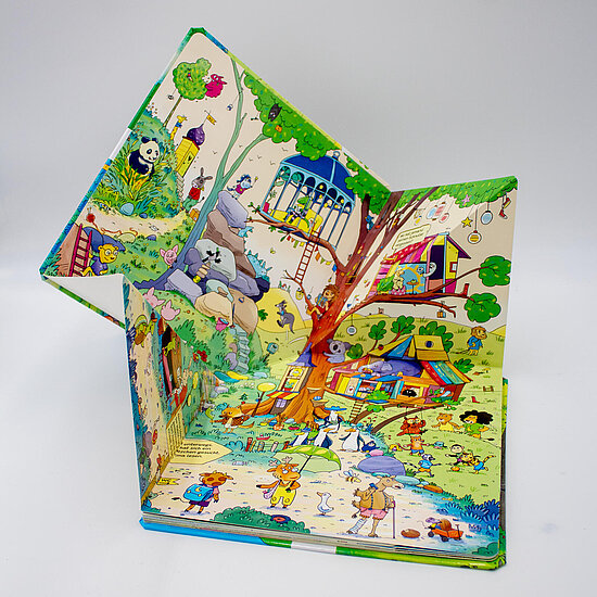 Das Buchcover zeigt einen bunten, geöffneten Pop-up-Wald mit großem Baum, Baumhäusern, spielenden Kindern und vielen Tieren in Grün und Blau.