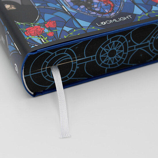 Das Buchcover zeigt einen blauen Mosaikhintergrund mit roten Rosen, runden Ornamenten am Buchschnitt und weissem Leseband.
