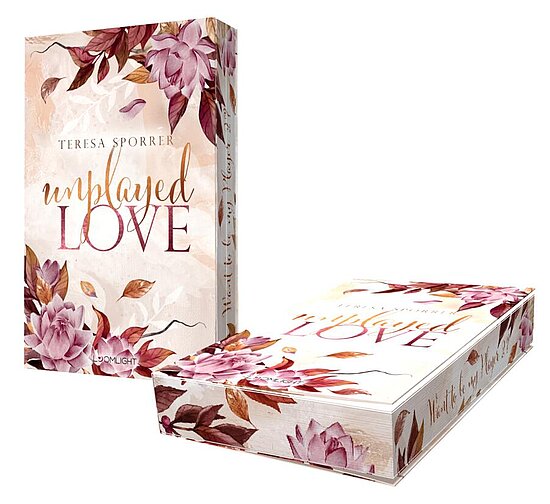 Das Buchcover zeigt zarte, rosa Blumen und Blätter auf einem hellen Hintergrund. Der Titel „unplayed LOVE“ ist in eleganten, goldenen Buchstaben hervorgehoben.