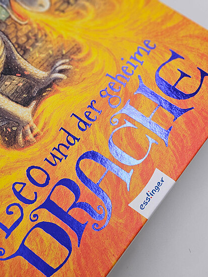 Das Buchcover zeigt vor orangegelbem Hintergrund einen sitzenden Jungen mit braunen Haaren und einem kleinen Drachen, Schriftzug in blau.