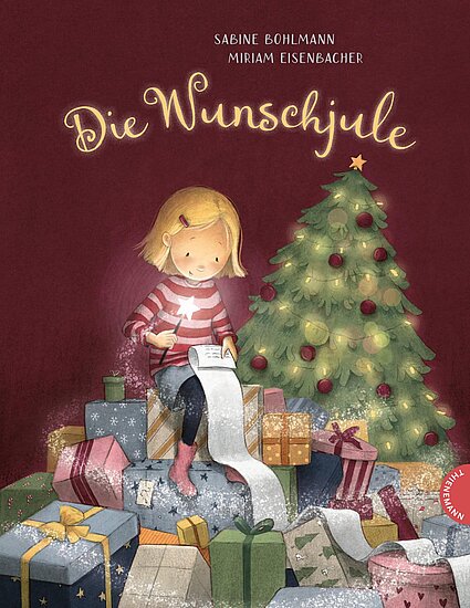 Das Buchcover zeigt ein Mädchen mit blonden Haaren in einem rot-weiß gestreiften Pullover, das an einem langen Wunschzettel sitzt. Im Hintergrund steht ein geschmückter Weihnachtsbaum, umgeben von bunten Geschenken.
