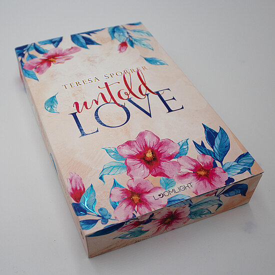 Das Buchcover zeigt … eine cremefarbene Fläche mit großen pinken Aquarellblüten, türkisblauen Blättern und dem Titel in dunkelblauer Schrift.